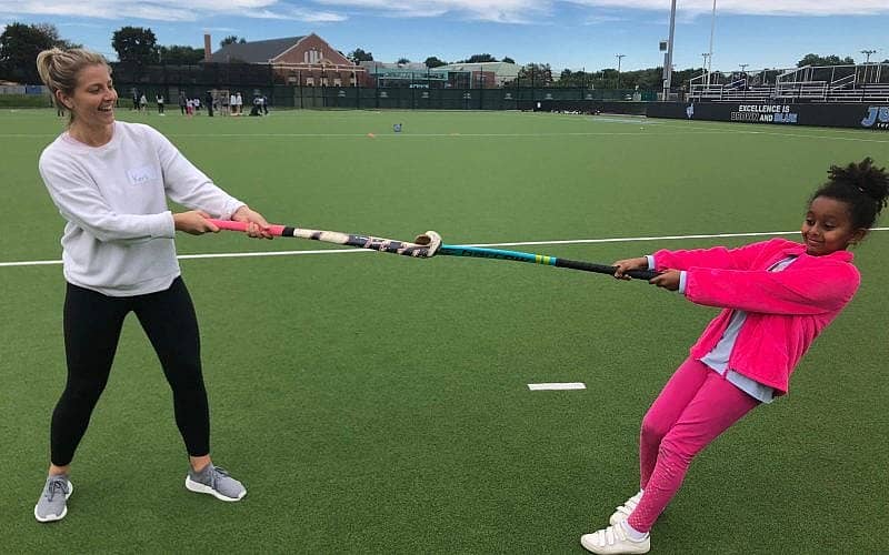 big and little sister on a sports field playing tug o war