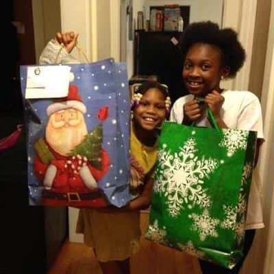 little sisters holding up Christmas themed gift bags