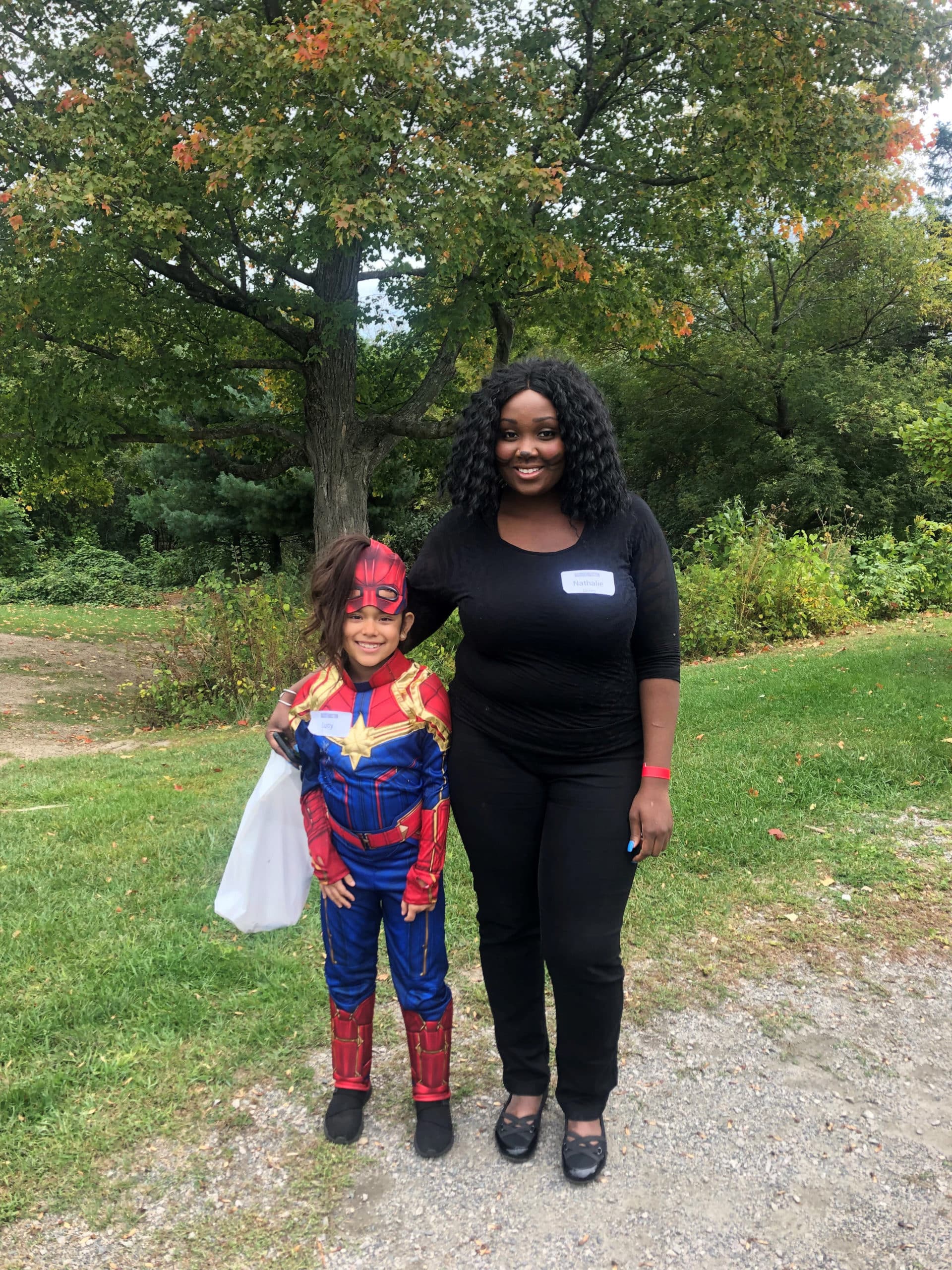 picture of a girl dressed in a super hero costume standing next to a woman
